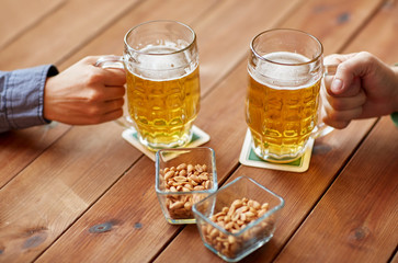 close up of hands with beer mugs at bar or pub