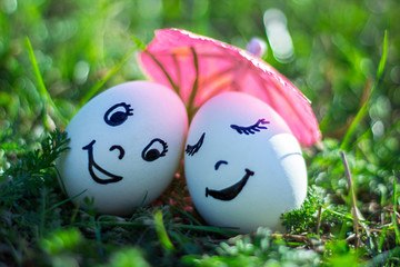 Funny eggs imitating happy couple of smiling lovers under umbrel