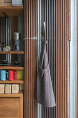 Apron hanging on tin wall in coffee shop with cups on shelf