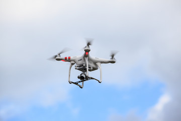 Drone with high resolution digital camera flying on the cloud blue sky 