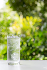 a glass of cold water with nature background.