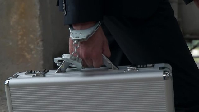 a man with a briefcase with handcuffs goes to a deal