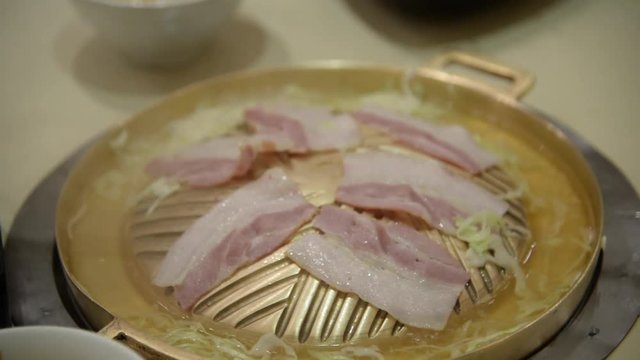 Korean grilled style on hot gold stove served with vegetables like needle-mushroom, pork and beef slices and bacon eating