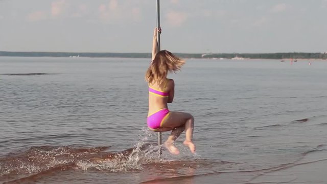 Beautiful girl dancing on a pole on the beach