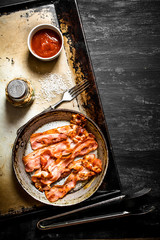 Fried bacon in a frying pan with the sauce.