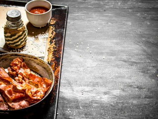 Fried bacon in a frying pan with the sauce.