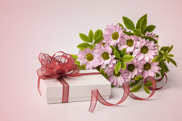 Gift box and beautiful flowers on pink background