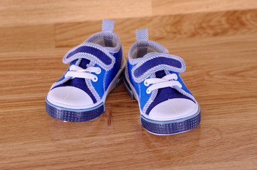 Pair of baby shoes on a wooden background.