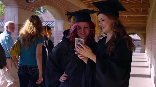 Two friends hugging and graduate while taking a picture