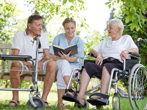 Carer reads a book to the elderly persons 