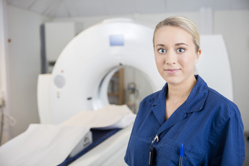 Young Professional Standing By MRI Machine In Hospital