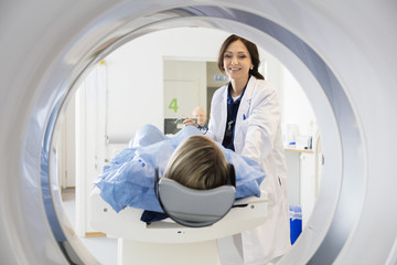 Female Doctor Looking At Patient Undergoing CT Scan - obrazy, fototapety, plakaty