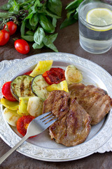 Grilled steak meat pork and grilled vegetables on brown stone ba