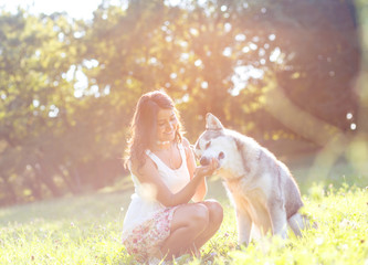 Young brunette woman playing with her dog in the park.