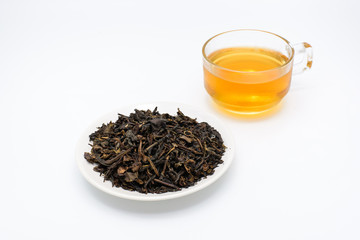 Clear glass of tea and dry tea leaves in a cup isolated on white