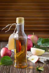 Apple cider vinegar in a glass bottle with fresh apples on a tab