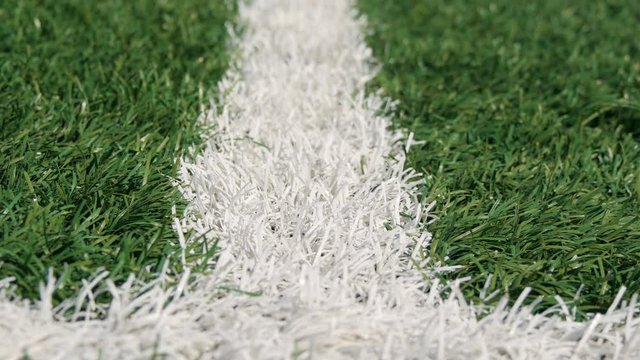 Close up of the out of bounds line on a turf football field. Green grass