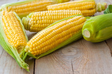 Fresh corn on cobs on wooden table 