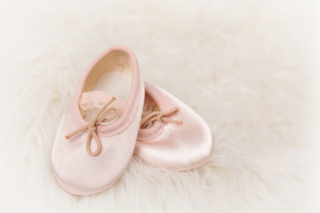 Light pink ballet dance shoes on a white fluffy background