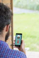 Young man seen from behind holding a smartphone with motorbike insurance concept on the screen. All graphics are made up.