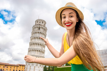Obraz premium Young female traveler having fun in front of the famous leaning tower in Pisa old town in Italy. Happy vacations in Italy