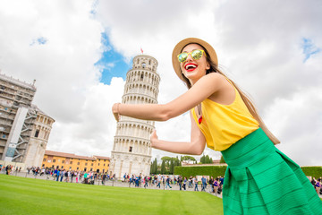 Young female traveler having fun in front of the famous leaning tower in Pisa old town in Italy....