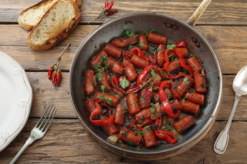 salsiccia piccante e peperoni in padella di metallo sfondo tavolo di cucina rustico
