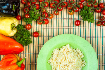 Selection of ingredients for cooking couscous: tomatoes, couscous, herbs, peppers; top view
