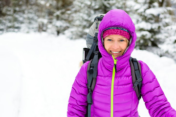 Happy woman walking in winter forest with backpack. Girl winter hiking backpacker.