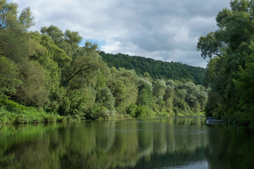 Летний пейзаж с видом реки и высоких берегов, заросших деревьями 