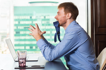 Angry red haired businessman chewing his tie