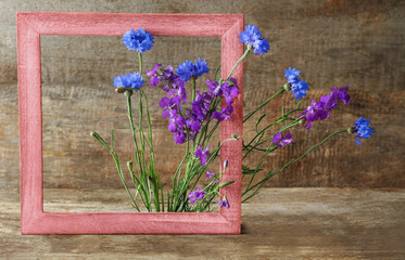 Retro frame with delphinium and bluettes on wooden background