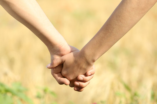 Young couple holding hands on beautiful field