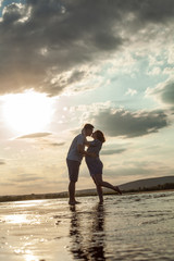 Happy couple is standing in the water and kissing.