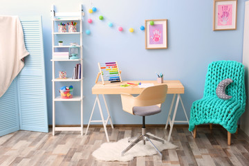 Wooden table in blue children room interior
