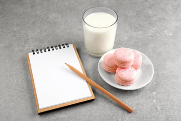 Notepad,milk and cookie on color background
