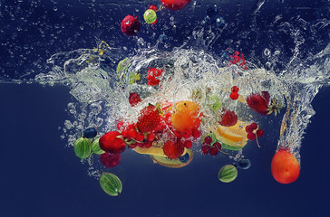 Fruits falling into water on  color background