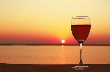 Glass of red wine on sunset background