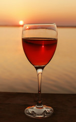 Glass of red wine on sunset background