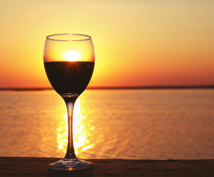 Glass Of Red Wine On Sunset Background