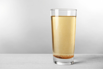 Glass with dirty water on light background