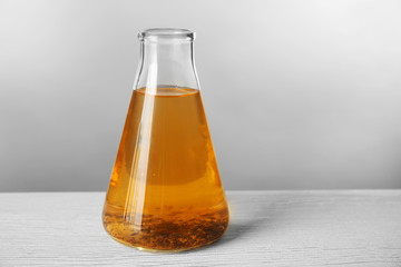 Flask with dirty water on light background