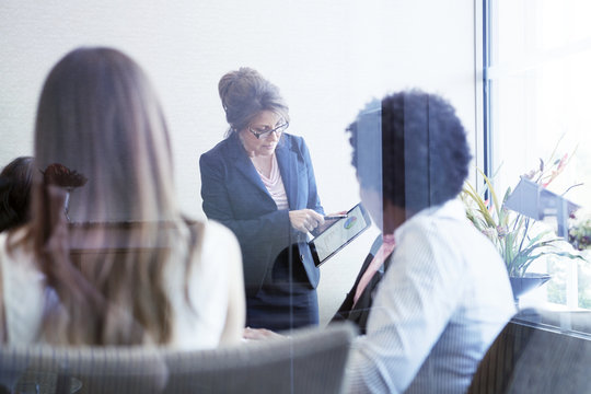 Businesswomen showing pie chart on tablet computer to colleagues