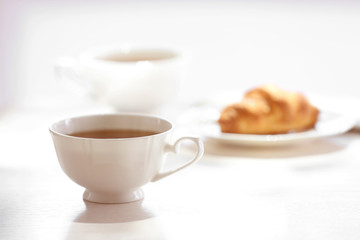 Cup of tea with croissant on table