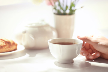 Female hand holding cup of tea on table