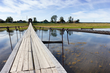 Rural landscape at summer with wooden suspension bridge
