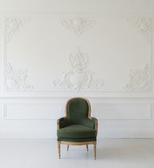 Living room with antique stylish green armchair on luxury white wall design bas-relief stucco mouldings roccoco elements