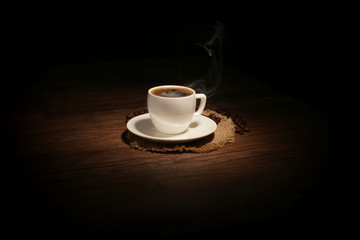 Cup of coffee with beans on wooden background