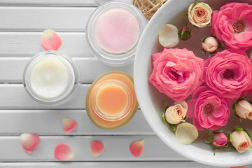 Composition with cosmetic cream and roses on wooden background