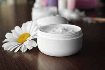 Fototapeta na wymiar Cosmetic cream and flower buds on wooden background